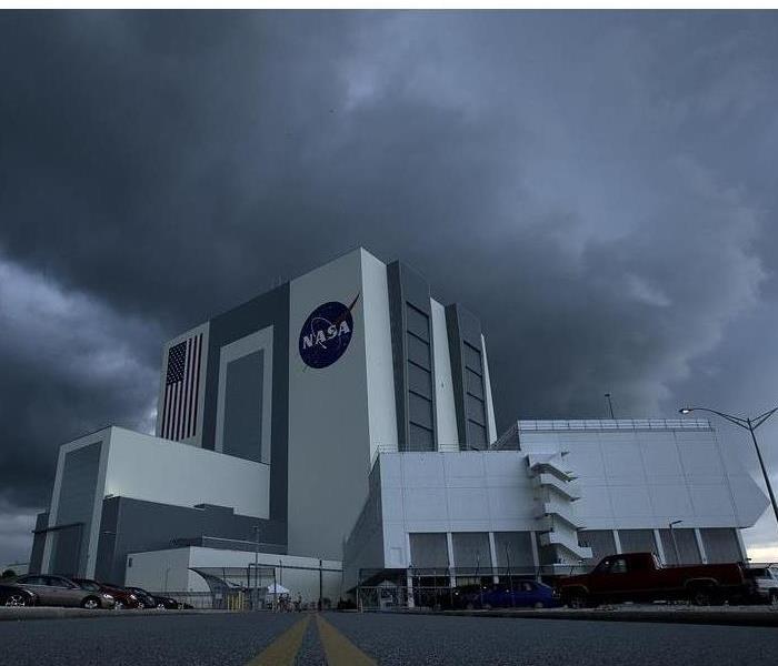 Dark gray storm cloud overhead a tall commercial building (NASA)